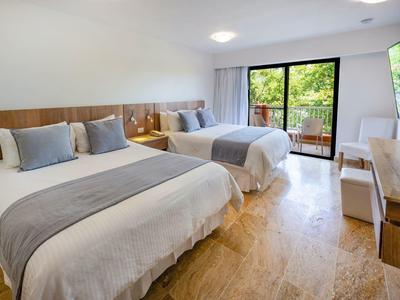 Modernes Hotelzimmer mit zwei Einzelbetten, Holzboden, Balkon und hellem, freundlichem Design.