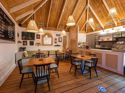 Gemütliches Café mit Holzboden, Tischen, Stühlen und Decke mit sichtbaren Holzbalken.