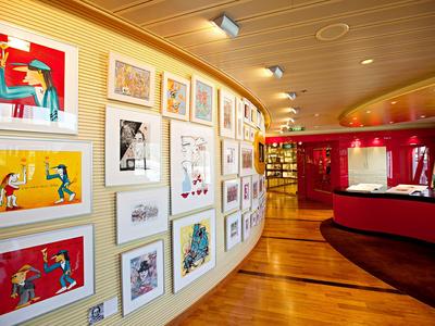 Kunstgalerie in einem Hotel mit farbenfrohen Gemälden an gebogener Wand und Holzfußboden.