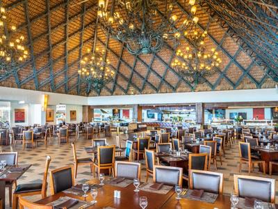 Großes Restaurant mit Holzdach, vielen Tischen, Stühlen und glänzenden Kronleuchtern.