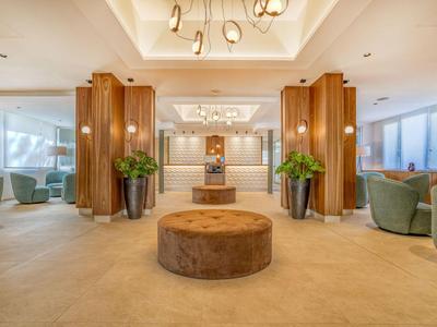 Elegante hotel lobby met comfortabele zitplaatsen, houten lambrisering en moderne verlichting.