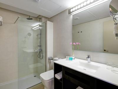 Moderne badkamer met grote douche, toilet en wastafel met spiegel en verlichting.