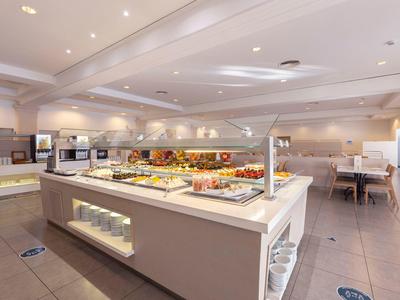 Postazione buffet in una sala da pranzo di un hotel luminosa con varie opzioni per la colazione.