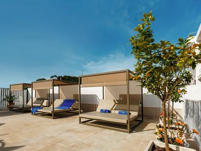 Trois chaises longues modernes avec coussins bleus sur une terrasse surplombant la mer sous un ciel dégagé.