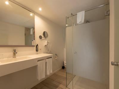 Modernes Badezimmer mit Waschbecken, Spiegel und Glasdusche in Beige- und Weißtönen.