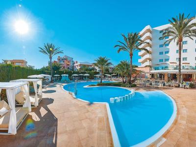 Modern hotel pool with loungers, palm trees, and high-rise building under a sunny sky