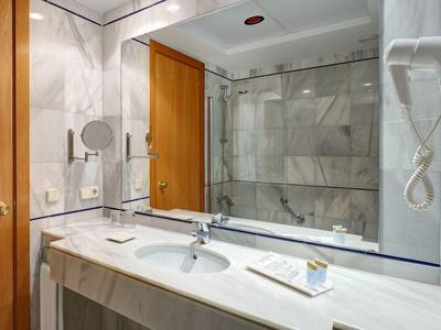 Baño moderno con espejo grande, lavabo y cabina de ducha con puerta de vidrio.