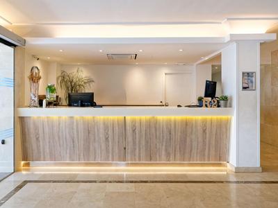 Modern hotel reception with illuminated wooden counter and minimalist decor.