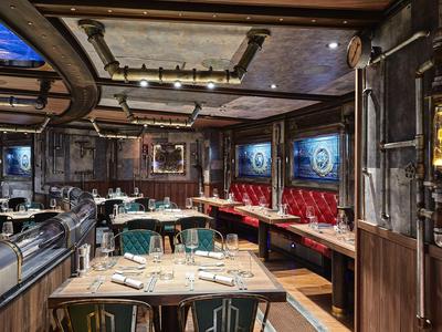 Ristorante accogliente con arredi in legno, panche rosse imbottite e tavoli apparecchiati.