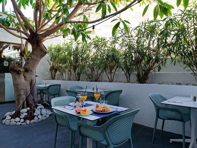 Spazio esterno accogliente con tavoli, sedie e un grande albero, ideale per i pasti.