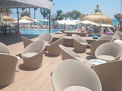 Outdoor terrace with round chairs overlooking a pool and the sea.