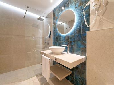 Moderne badkamer met verlichte ronde spiegel en inloopdouche.