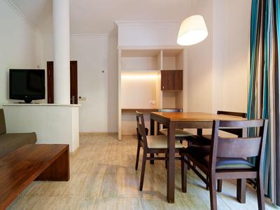 Modern eingerichteter Essbereich mit Holztisch und Stühlen neben einem Wohnzimmer mit Sofa und Fernseher.