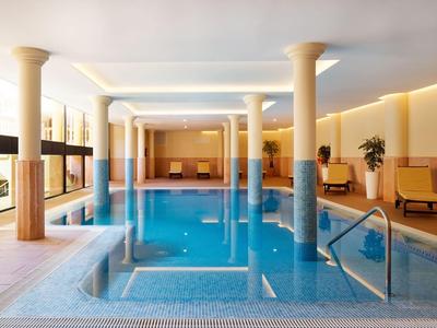 Piscine intérieure dans une pièce lumineuse avec colonnes et coins sièges