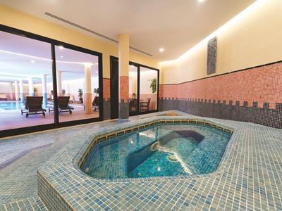 Bain à remous moderne dans un espace bien-être lumineux à côté d'une fenêtre en verre donnant sur la piscine.