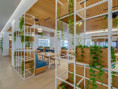 Restaurant d'hôtel moderne avec plafond en bois et plantes vertes suspendues comme séparateurs.