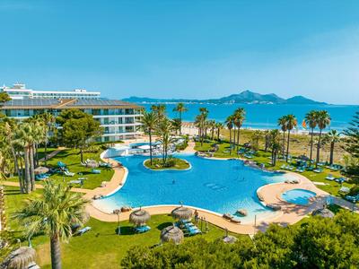 Großer Hotelpool mit Palmen und Meerblick an einem sonnigen Tag