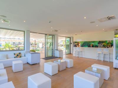 Espace lounge d'hôtel lumineux et moderne avec sièges cubes blancs et grandes fenêtres.