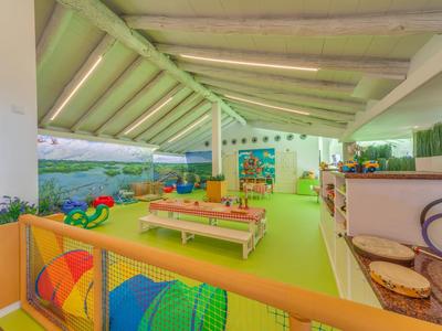 Salle de jeux intérieure lumineuse avec tapis vert, jouets colorés et meubles en bois sous toit incliné