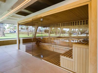 Espace sauna avec boiseries et grandes fenêtres donnant sur l'extérieur.