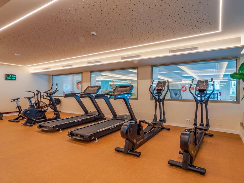 Salle de sport moderne avec tapis roulants et elliptique devant de grandes fenêtres