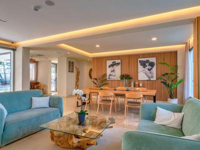 Modernes Wohnzimmer mit blauen Sofas, Glastisch und beleuchtetem Holztisch im Hintergrund.