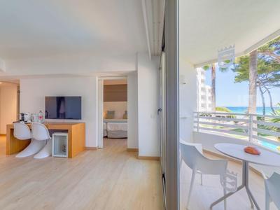 Helles Hotelzimmer mit Wohnzimmer, Schlafzimmer und Balkon mit Meerblick.