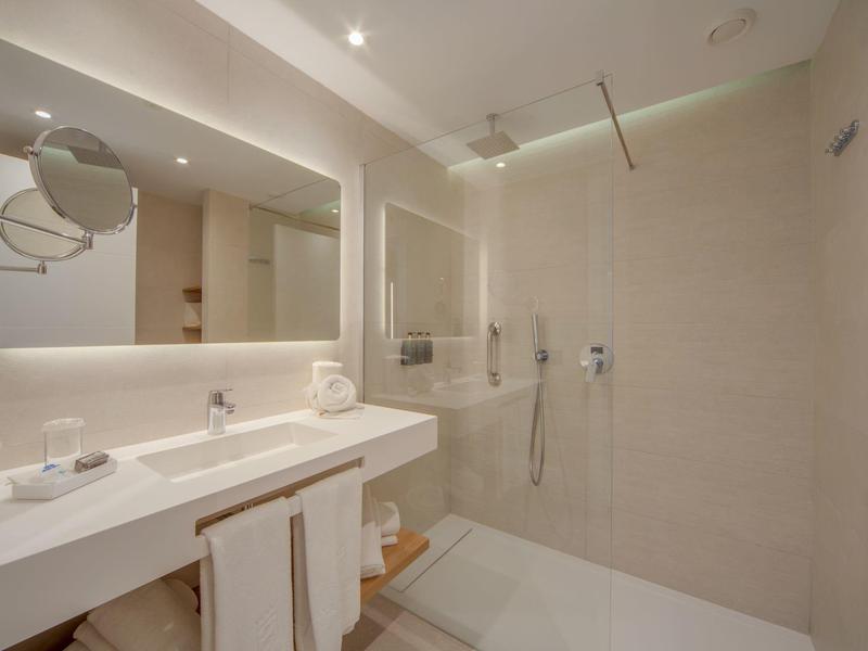 Modernes Badezimmer mit Duschbereich und doppelseitigem Waschbecken in neutralen Tönen.