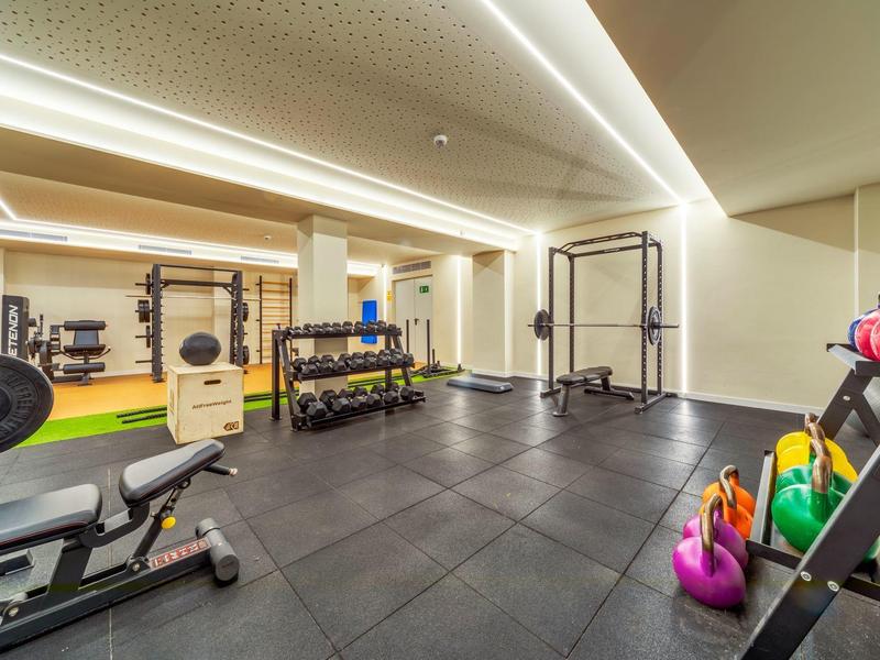 Moderner Fitnessraum mit Gewichten, Kettlebells und Trainingsgeräten in einem Hotel.
