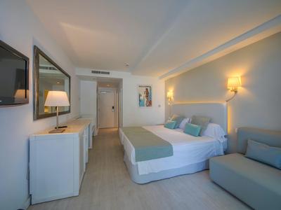 Modernes Hotelzimmer mit Doppelbett, Sofa, TV und minimalistischem Dekor.