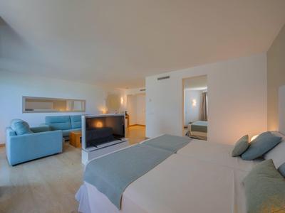 Modernes Hotelzimmer mit großem Bett, Fernseher und Sitzecke in ruhigen Farben.