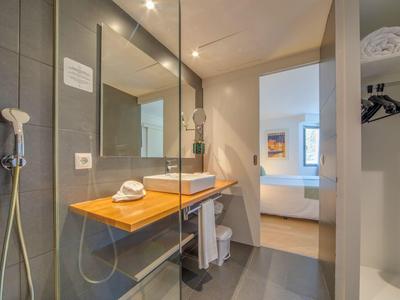 Modernes Badezimmer mit Glasdusche, Holztisch und Waschbecken in einem Hotelzimmer.