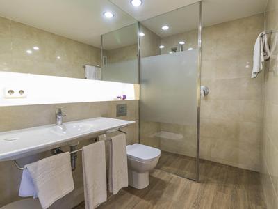 Modern bathroom with large mirror, long vanity, toilet, and walk-in shower.