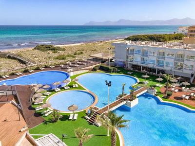 Hotel mit mehreren Pools und Liegen an der Küste mit Blick auf das Meer und den Strand.