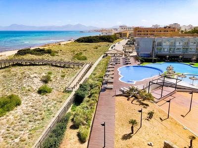 Vista di una piscina dell'hotel con sdraio accanto a una spiaggia di sabbia e al mare.
