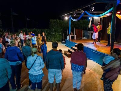 People watch an outdoor nighttime stage performance at an event.