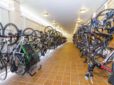 Bicycles are neatly parked on both sides of a long, well-lit corridor in a facility.