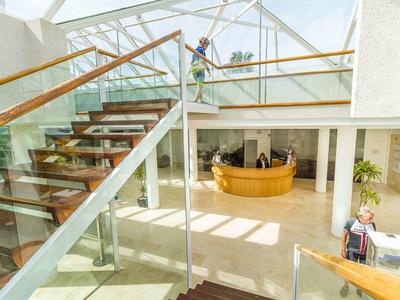 Área interior moderna de un hotel con escalera de madera y recepción luminosa.