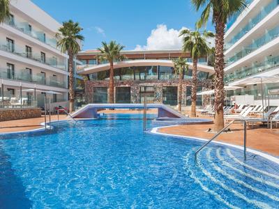 Modern outdoor pool surrounded by lounge chairs and palm trees at a hotel.