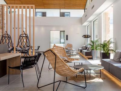 Modernes Wohnzimmer mit Holzboden, großen Fenstern, Lounge-Stühlen und grauem Sofa.