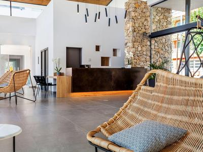 Salón de hotel moderno con interior luminoso, cómodas sillas de mimbre y decoración de pared de piedra