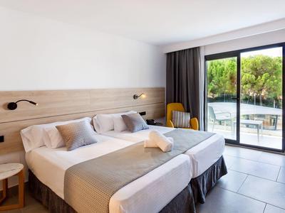 Modernes Hotelzimmer mit zwei Einzelbetten, Holzverkleidung und Blick auf Terrasse mit See.