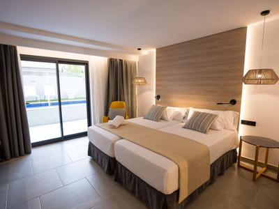 Modern eingerichtetes Hotelzimmer mit zwei Einzelbetten und Zugang zu einem Balkon.