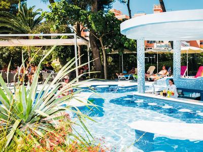 Basen z barem swim-up i strefą wypoczynkową w tropikalnym hotelu