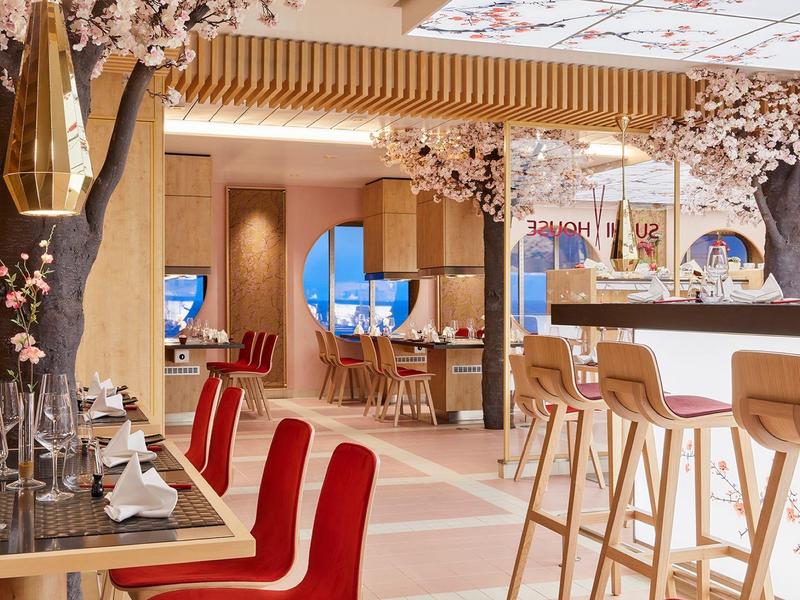 Nowoczesne wnętrze restauracji z czerwonymi siedzeniami i kwiatowymi dekoracjami.