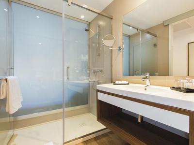 Modern bathroom with a glass shower enclosure, white double sink, and large mirror.