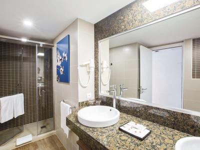 Salle de bain moderne avec douche, lavabo rond, grand miroir et comptoir en granit.
