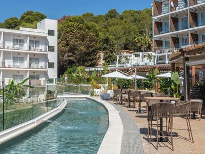 Terrazza dell'hotel con piscina e posti a sedere all'aperto accanto a edifici moderni e alberi sullo sfondo.