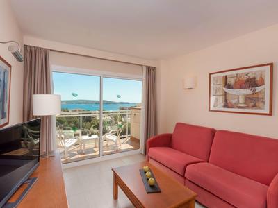 Bright living room with red sofa, large window, and view of terrace and sea.