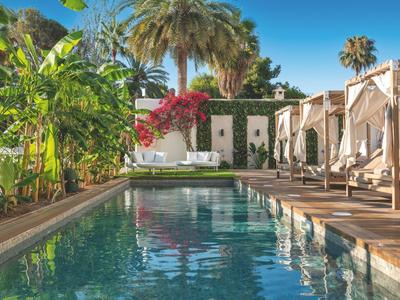 Pool area with loungers, plants, and sunshades in a tropical hotel setting.